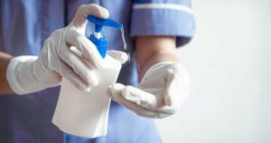 Nurse with gloves putting on hand sanitizer